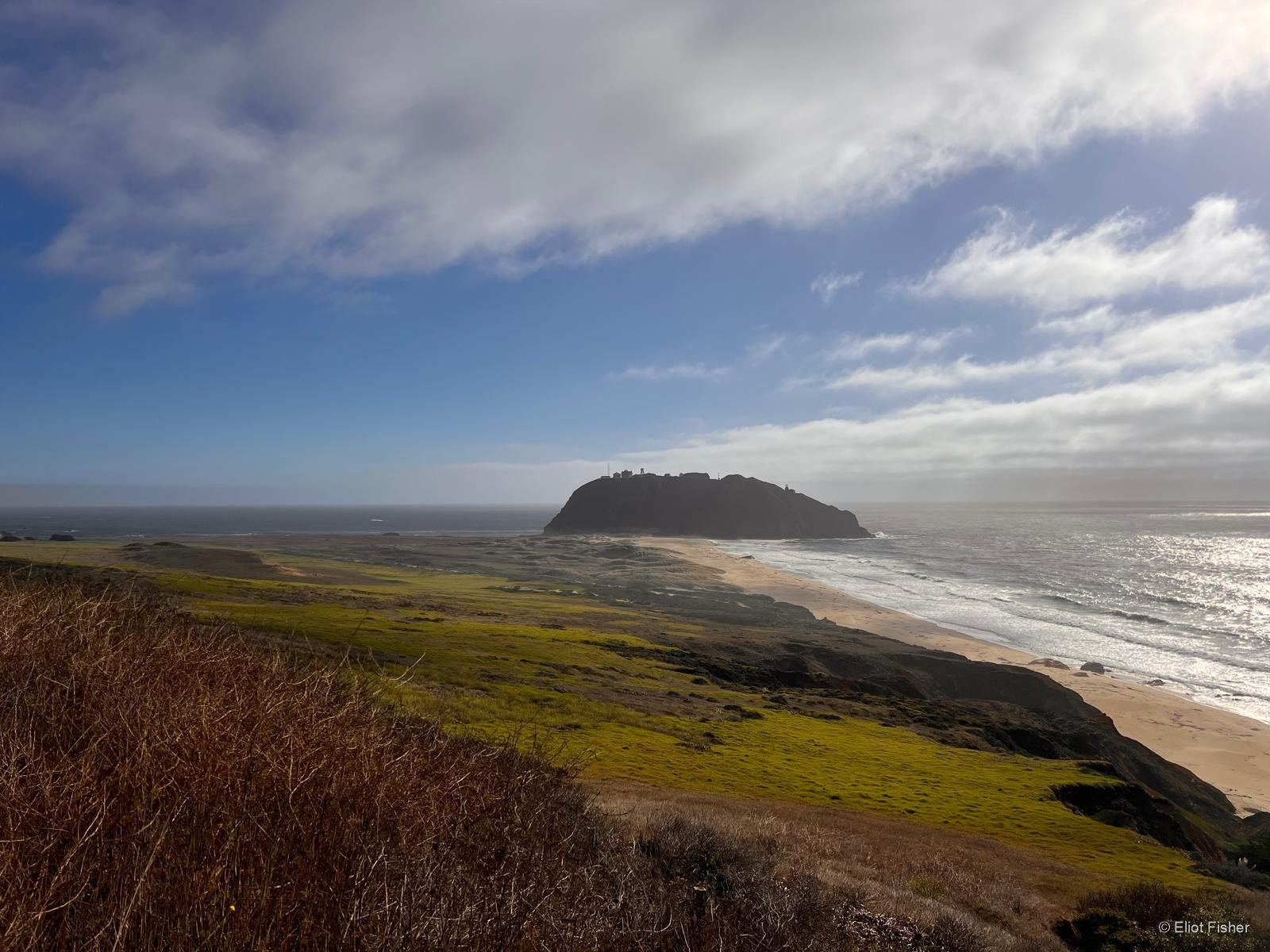 Eliot Fisher’s photograph of an island off a green coastal headland